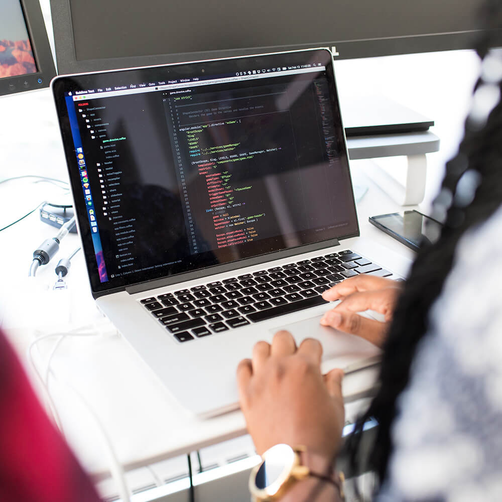 image of a woman using two computers with code