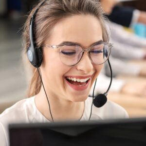 Woman with headset smiling while working on a computer