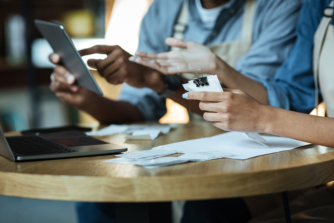 Financial problems and closure of small businesses during COVID-19 quarantine. African american female and male in aprons check financial accounts with tablet and laptop in cafeteria, cropped